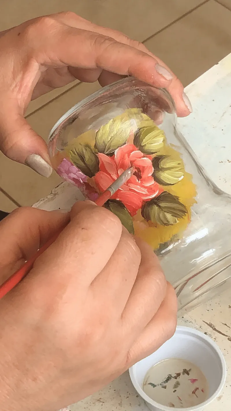 Aluna pintando rosa em pote de vidro durante a aula online